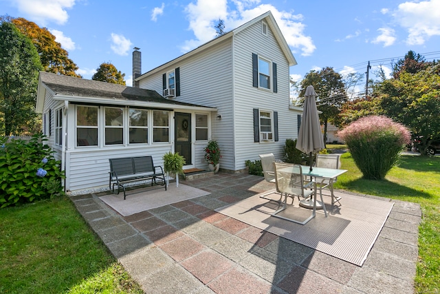 rear view of property with a lawn, a patio area, and a sunroom