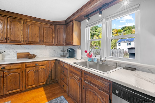 kitchen featuring backsplash, light hardwood / wood-style flooring, stainless steel dishwasher, and sink