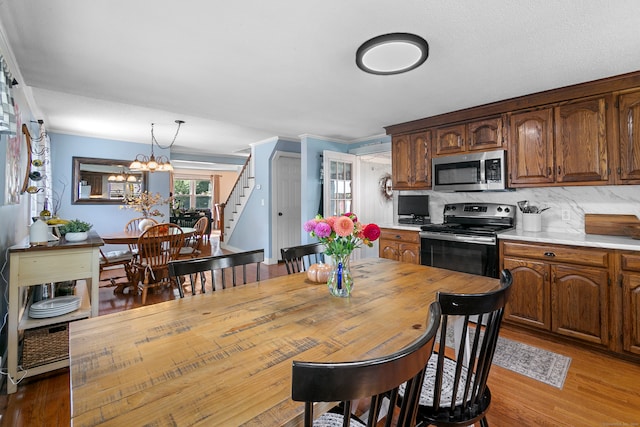 kitchen with a chandelier, tasteful backsplash, hardwood / wood-style floors, decorative light fixtures, and appliances with stainless steel finishes