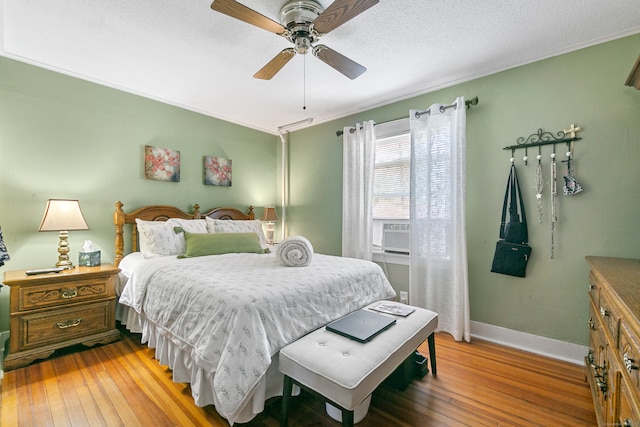 bedroom with cooling unit, ceiling fan, hardwood / wood-style floors, and a textured ceiling