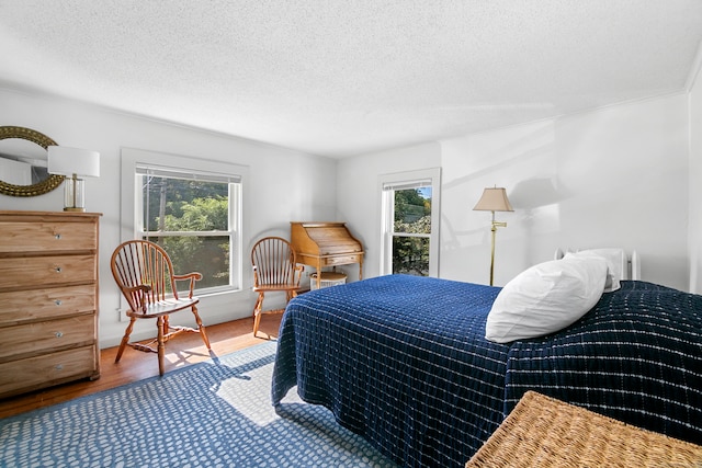 bedroom with multiple windows, wood-type flooring, and a textured ceiling