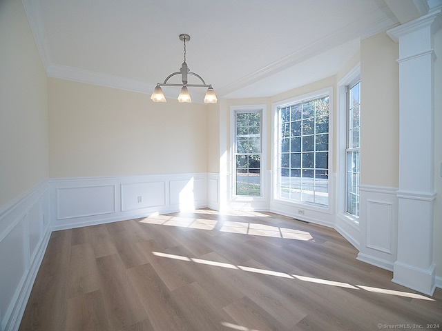 spare room with ornamental molding, a notable chandelier, ornate columns, and light hardwood / wood-style floors