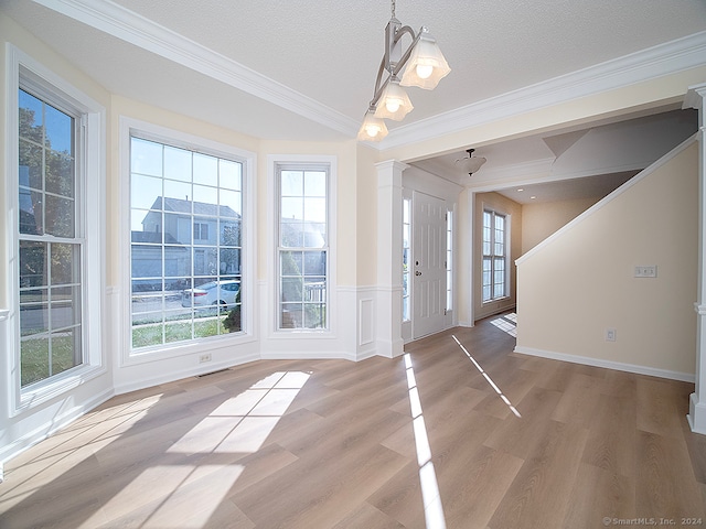 entryway with plenty of natural light, crown molding, light hardwood / wood-style flooring, and a textured ceiling