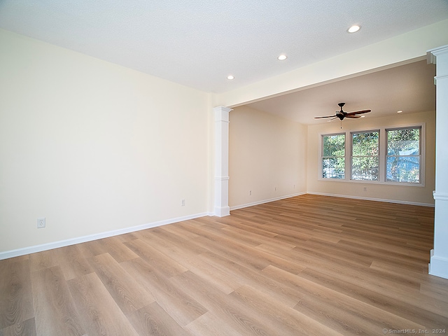 unfurnished room featuring a textured ceiling, decorative columns, and light hardwood / wood-style floors