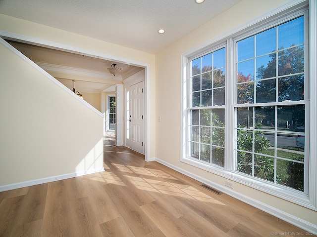 entrance foyer with a textured ceiling, light hardwood / wood-style flooring, plenty of natural light, and lofted ceiling with beams