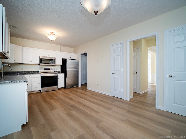 kitchen featuring sink, light hardwood / wood-style floors, white cabinetry, appliances with stainless steel finishes, and a textured ceiling