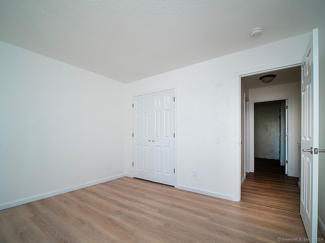 spare room featuring light hardwood / wood-style floors and a textured ceiling