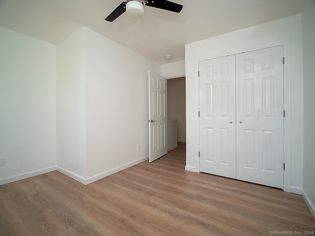 unfurnished bedroom with a closet, light hardwood / wood-style flooring, a textured ceiling, and ceiling fan