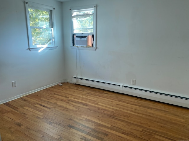 spare room featuring cooling unit, hardwood / wood-style flooring, and a baseboard heating unit