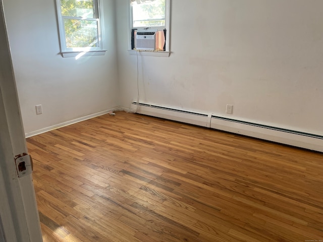 empty room with baseboard heating, cooling unit, and light hardwood / wood-style flooring