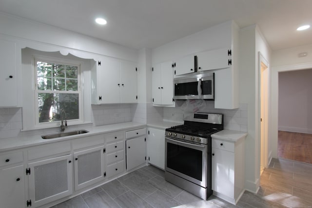 kitchen featuring decorative backsplash, stainless steel appliances, sink, white cabinets, and light hardwood / wood-style floors