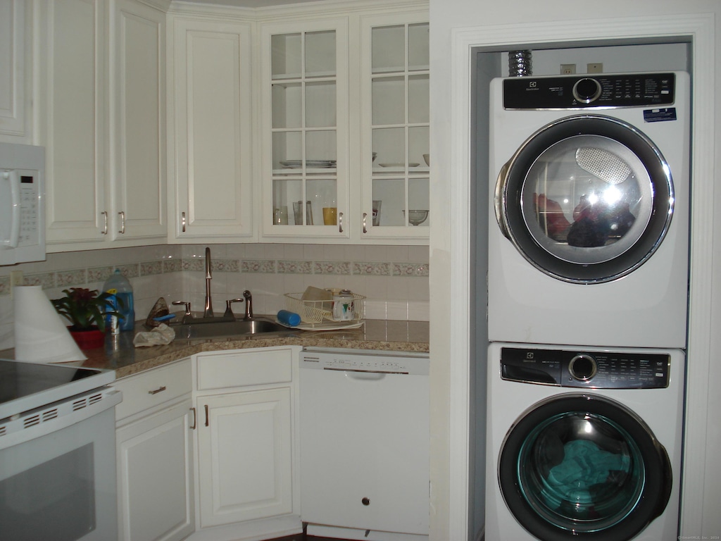 clothes washing area featuring sink and stacked washer / dryer