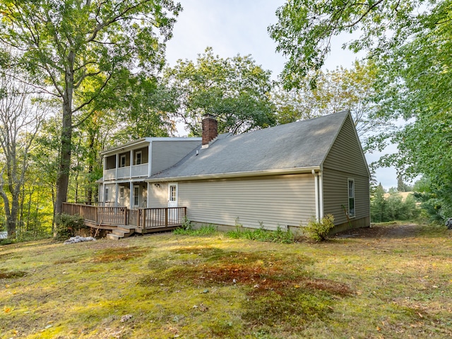 rear view of property featuring a lawn and a deck