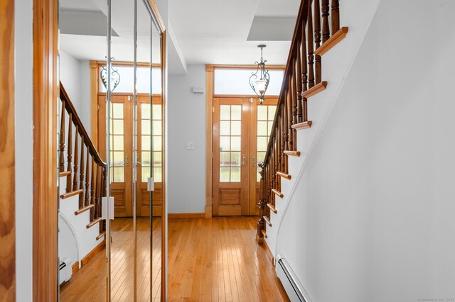 entrance foyer featuring french doors, baseboard heating, and light wood-type flooring