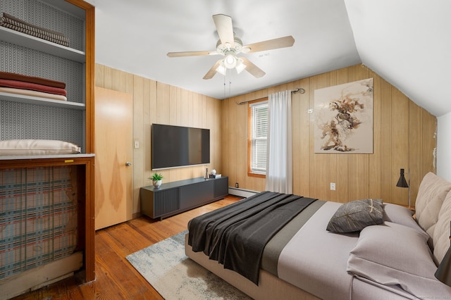 bedroom featuring wooden walls, ceiling fan, hardwood / wood-style floors, vaulted ceiling, and baseboard heating