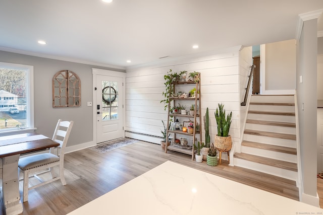 entrance foyer featuring light wood-type flooring, baseboard heating, and ornamental molding