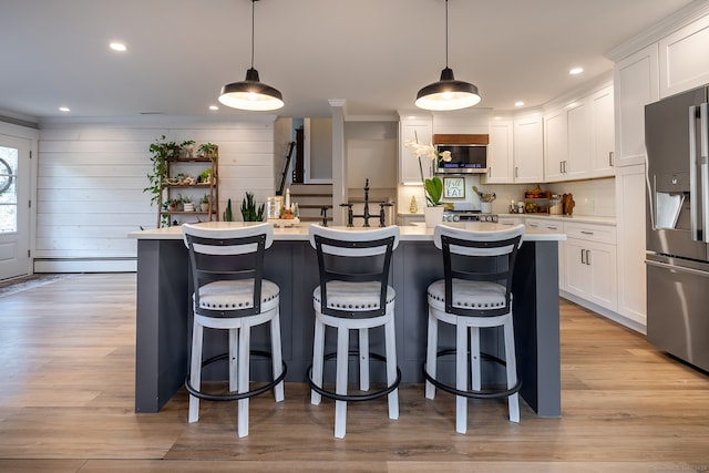 kitchen with stainless steel appliances, baseboard heating, pendant lighting, a center island with sink, and white cabinetry