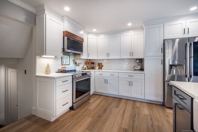 kitchen with tasteful backsplash, white cabinets, stainless steel appliances, and light hardwood / wood-style floors