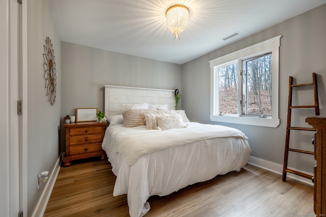 bedroom with a chandelier and light hardwood / wood-style floors