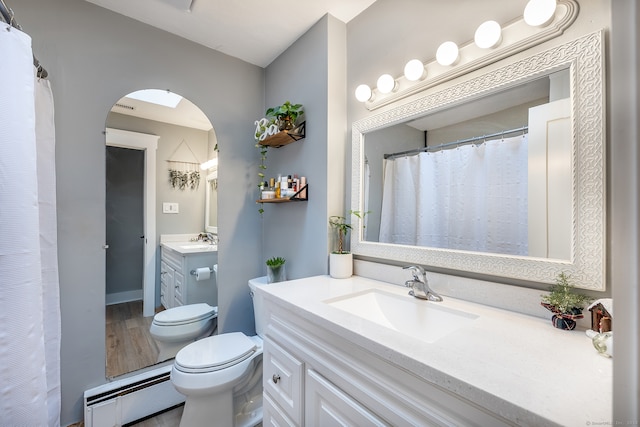 bathroom with hardwood / wood-style floors, vanity, toilet, and a baseboard heating unit