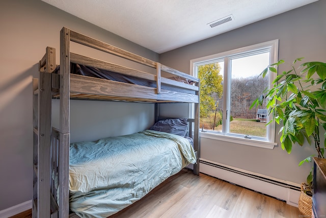 bedroom featuring hardwood / wood-style flooring and a baseboard radiator