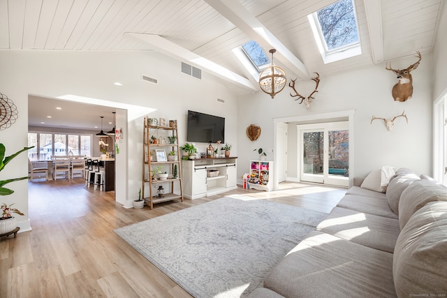 living room with light hardwood / wood-style floors, high vaulted ceiling, a skylight, and a notable chandelier