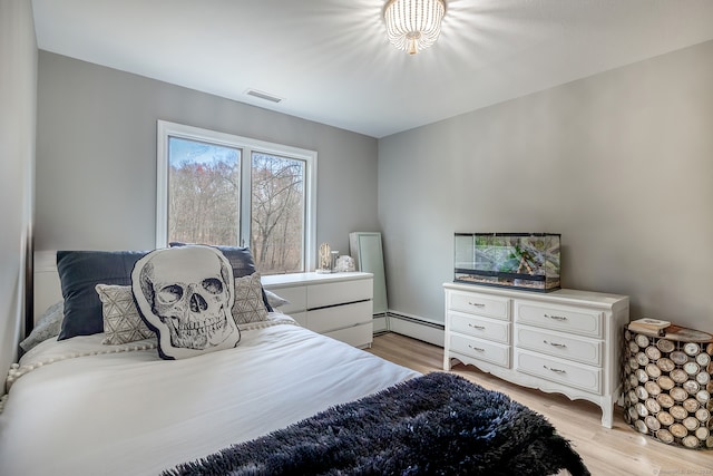 bedroom featuring light hardwood / wood-style floors and a baseboard heating unit