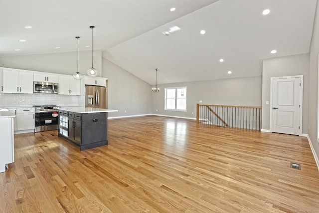 kitchen with pendant lighting, a center island, light wood-type flooring, appliances with stainless steel finishes, and white cabinetry