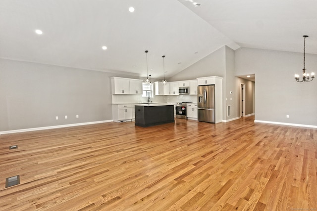 unfurnished living room with sink, high vaulted ceiling, light hardwood / wood-style floors, and an inviting chandelier