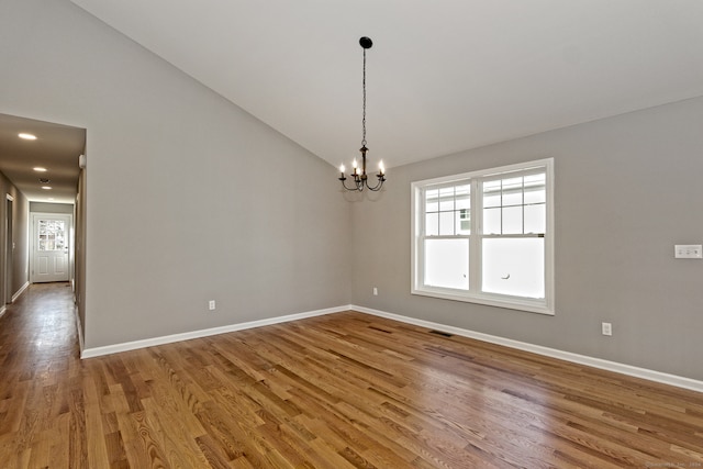 spare room featuring a chandelier, wood-type flooring, and lofted ceiling