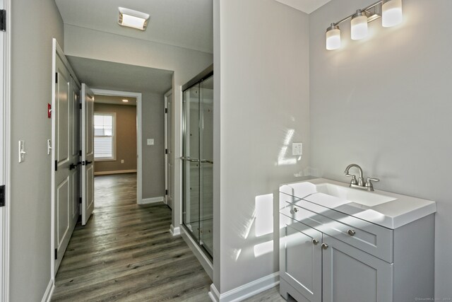 bathroom with vanity, a shower with shower door, and hardwood / wood-style flooring