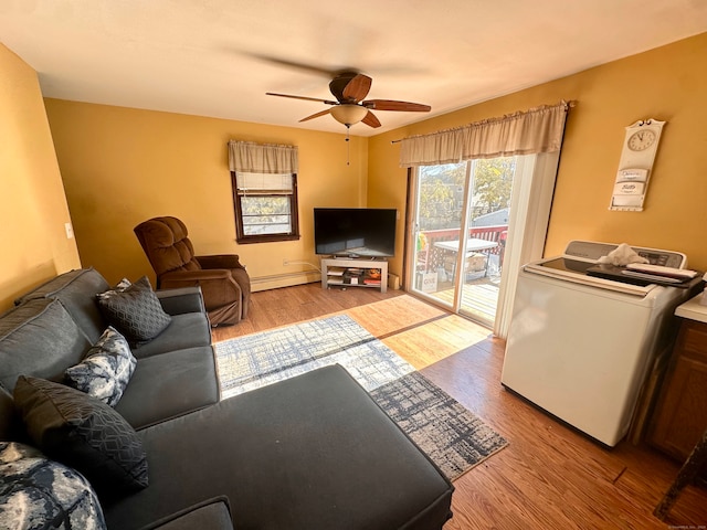 living room with baseboard heating, washer / clothes dryer, ceiling fan, and light hardwood / wood-style floors