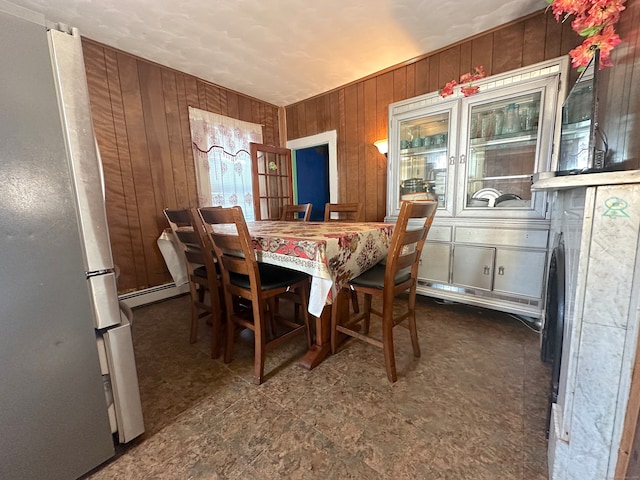 dining area featuring wood walls and a baseboard radiator