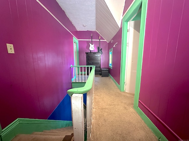 hall with lofted ceiling, carpet floors, and a textured ceiling