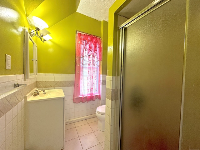 bathroom featuring tile patterned flooring, toilet, tile walls, vanity, and a textured ceiling