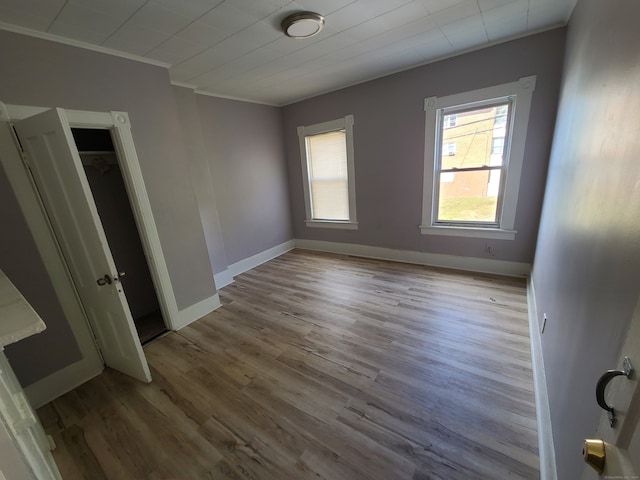 unfurnished bedroom featuring a closet, ornamental molding, and light wood-type flooring