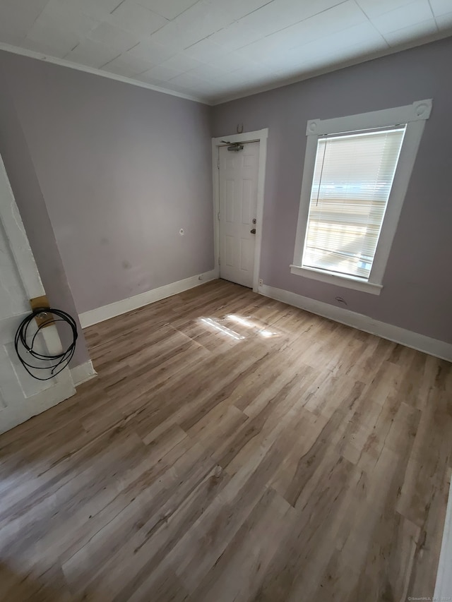 spare room featuring crown molding and light hardwood / wood-style floors