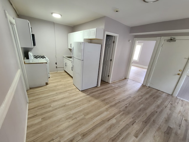 kitchen with white appliances, white cabinets, and light wood-type flooring