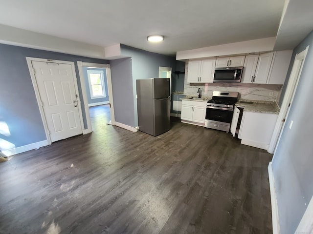 kitchen with light stone counters, sink, stainless steel appliances, dark hardwood / wood-style flooring, and decorative backsplash