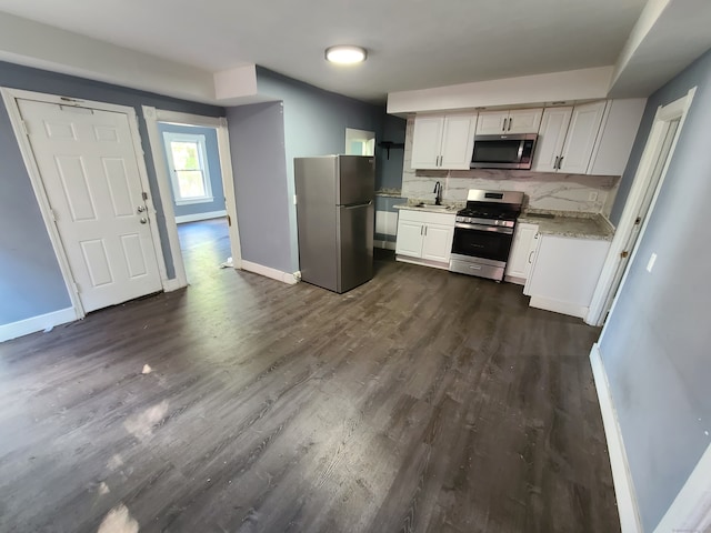 kitchen featuring dark hardwood / wood-style flooring, decorative backsplash, light stone countertops, white cabinets, and appliances with stainless steel finishes