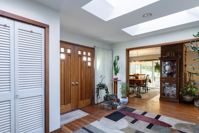 foyer featuring a chandelier, wood-type flooring, and a skylight