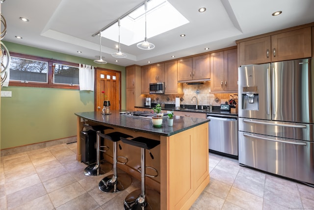 kitchen with a center island, stainless steel appliances, a tray ceiling, and sink