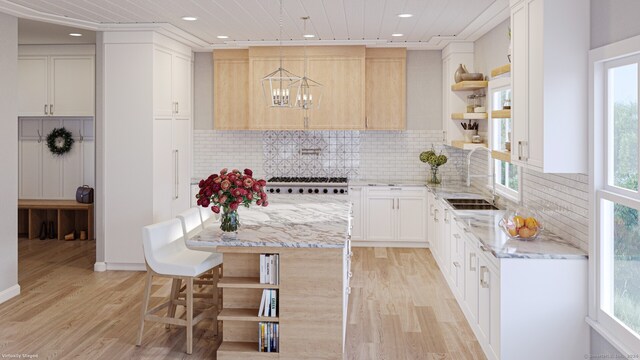 kitchen featuring pendant lighting, sink, white cabinetry, backsplash, and light hardwood / wood-style floors