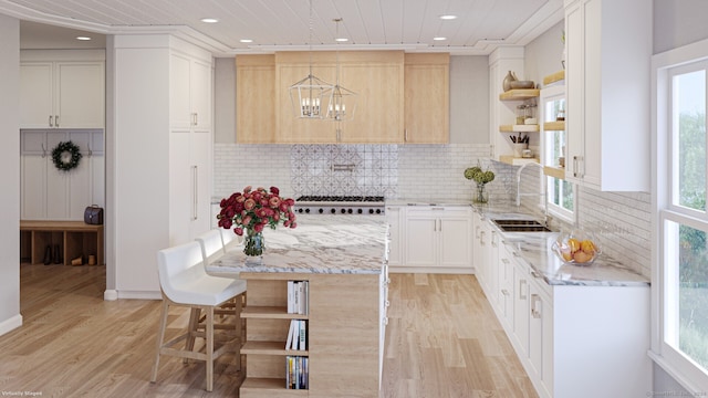 kitchen with light wood finished floors, open shelves, tasteful backsplash, a sink, and light stone countertops