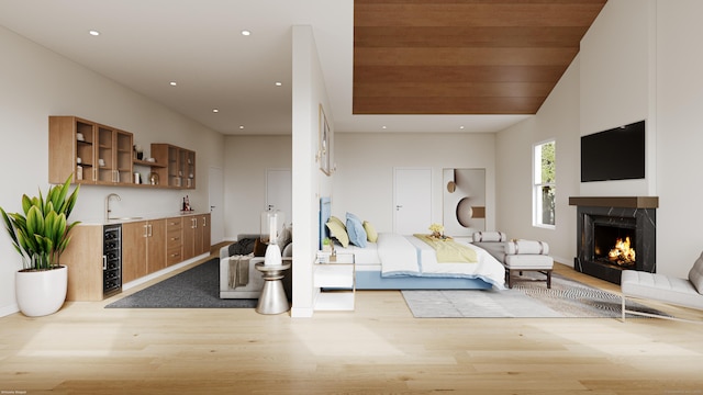 bedroom with recessed lighting, a sink, wood finished floors, wet bar, and a lit fireplace