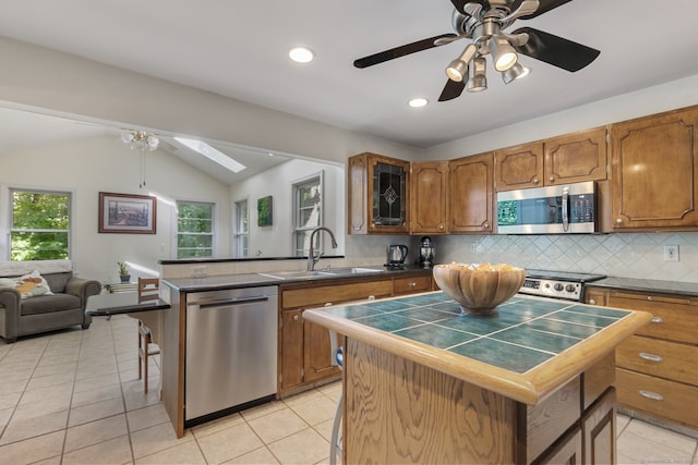 kitchen with a center island, sink, appliances with stainless steel finishes, lofted ceiling with skylight, and a kitchen bar