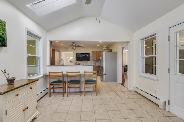 dining area featuring light tile patterned floors, lofted ceiling with skylight, and a baseboard heating unit