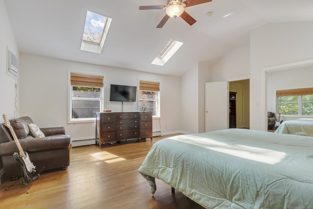 bedroom with vaulted ceiling with skylight, a baseboard heating unit, light wood-type flooring, and ceiling fan