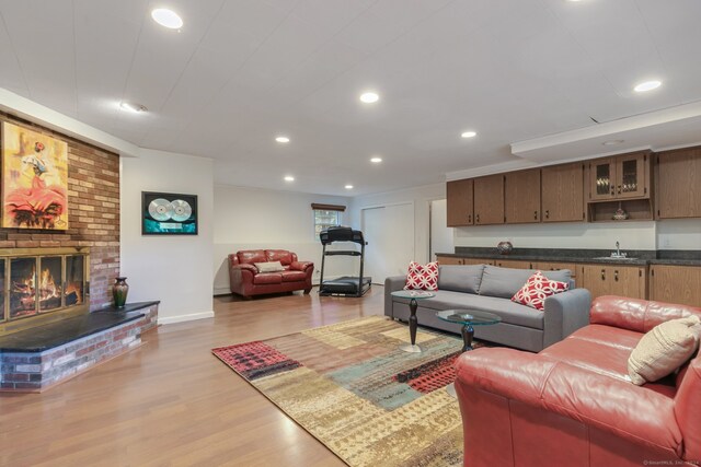 living room featuring a brick fireplace, wet bar, and light wood-type flooring