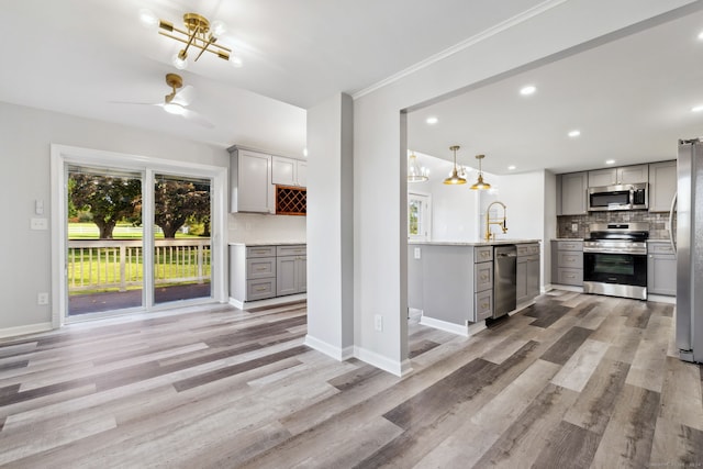 kitchen featuring decorative backsplash, stainless steel appliances, light hardwood / wood-style floors, gray cabinets, and decorative light fixtures